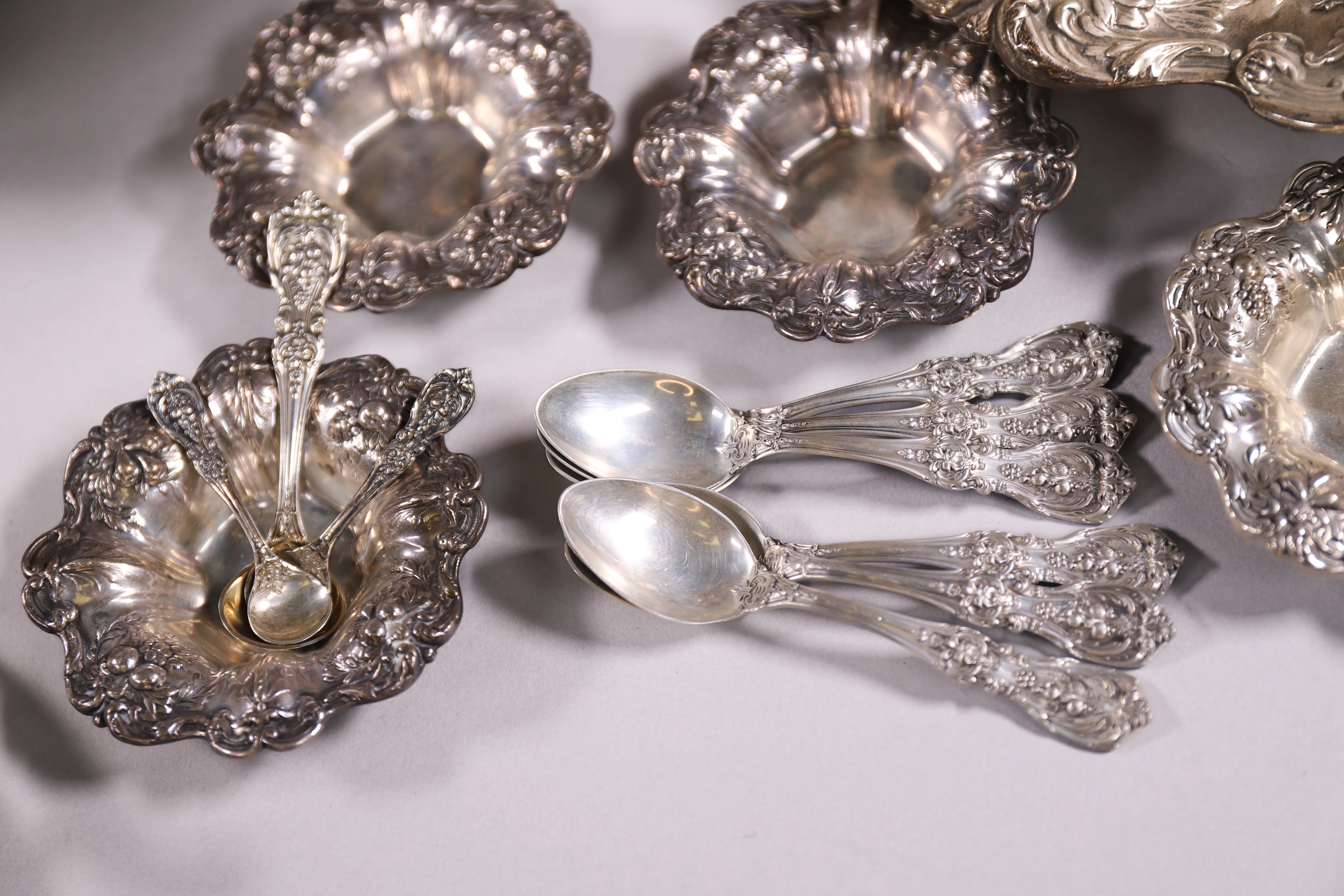 Detailed sterling silver place settings arranged for estate sale evaluation.